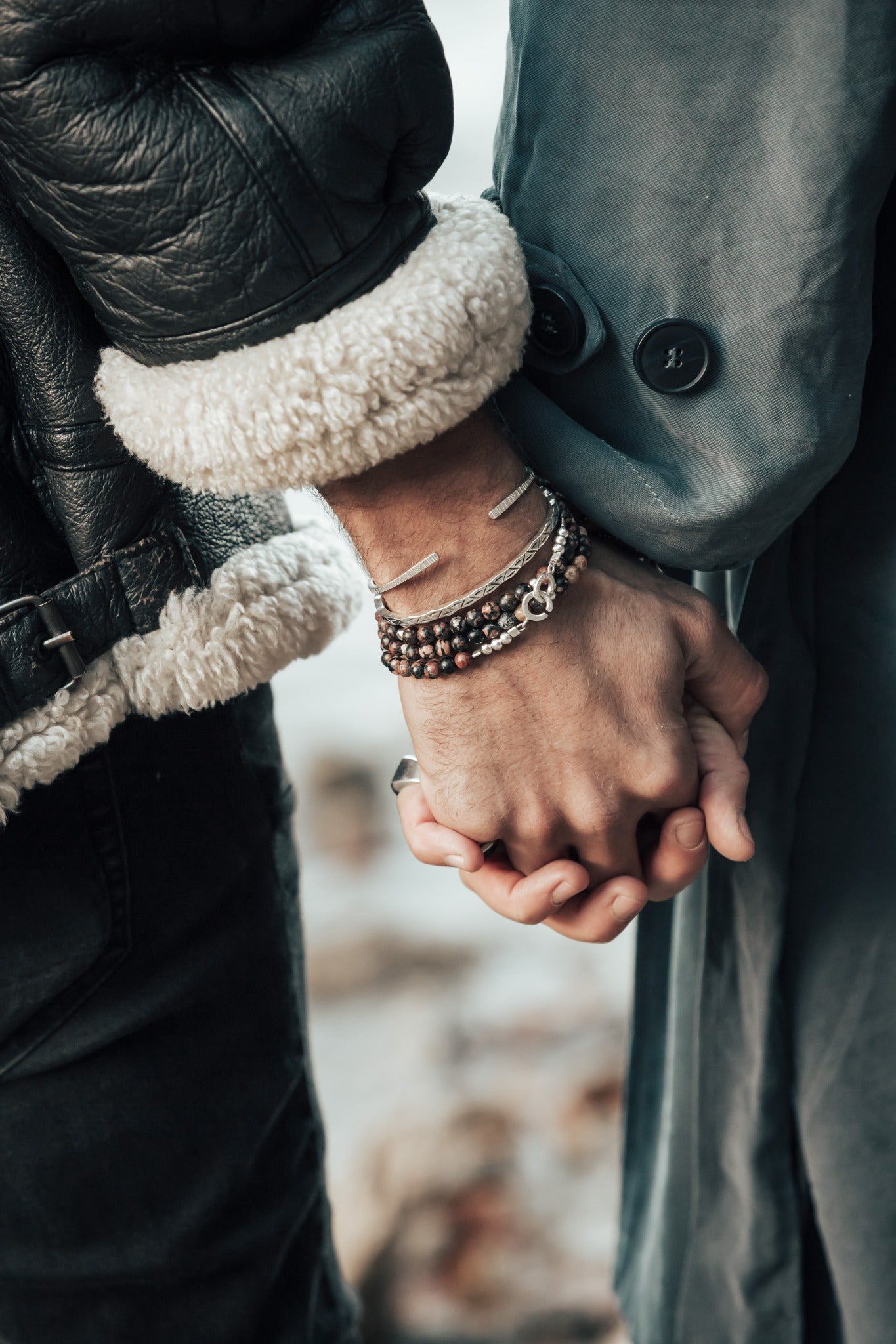 Nahaufnahme von zwei ineinander verschränkten Händen, mit originalen JALA-KORSAR-Armbändern